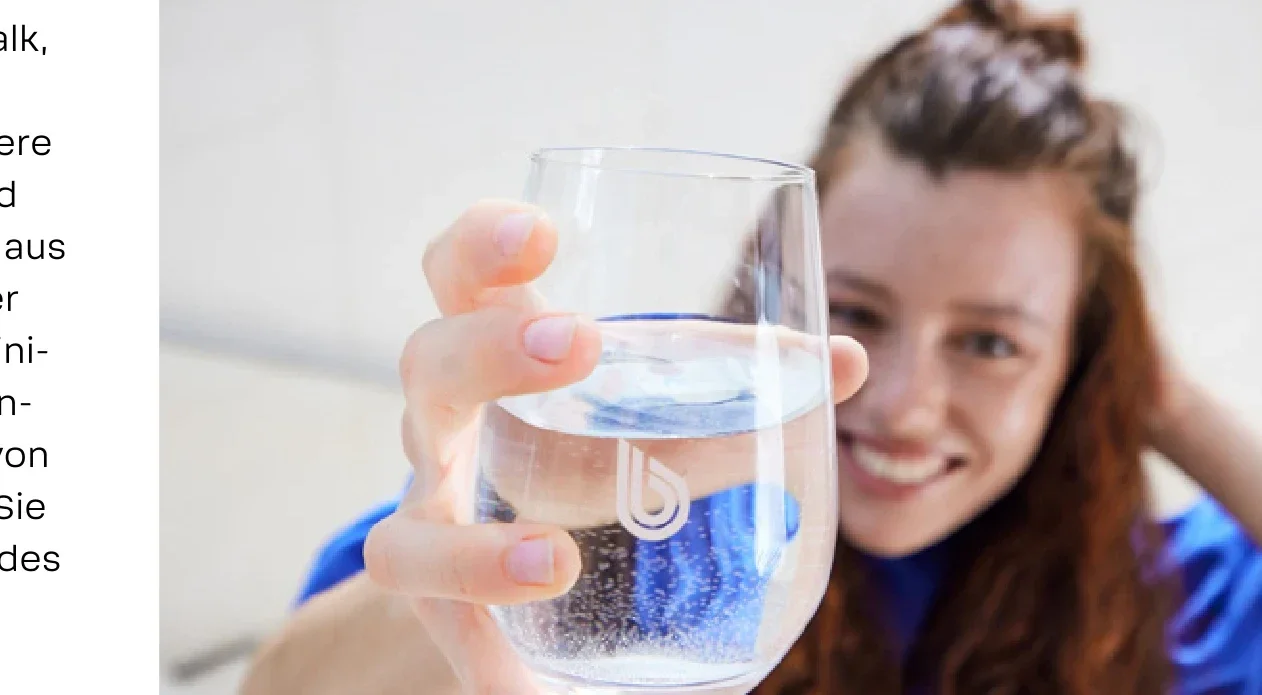Person hält ein glänzendes, sauberes Glas hoch – Sinnbild für weniger Kalkflecken
