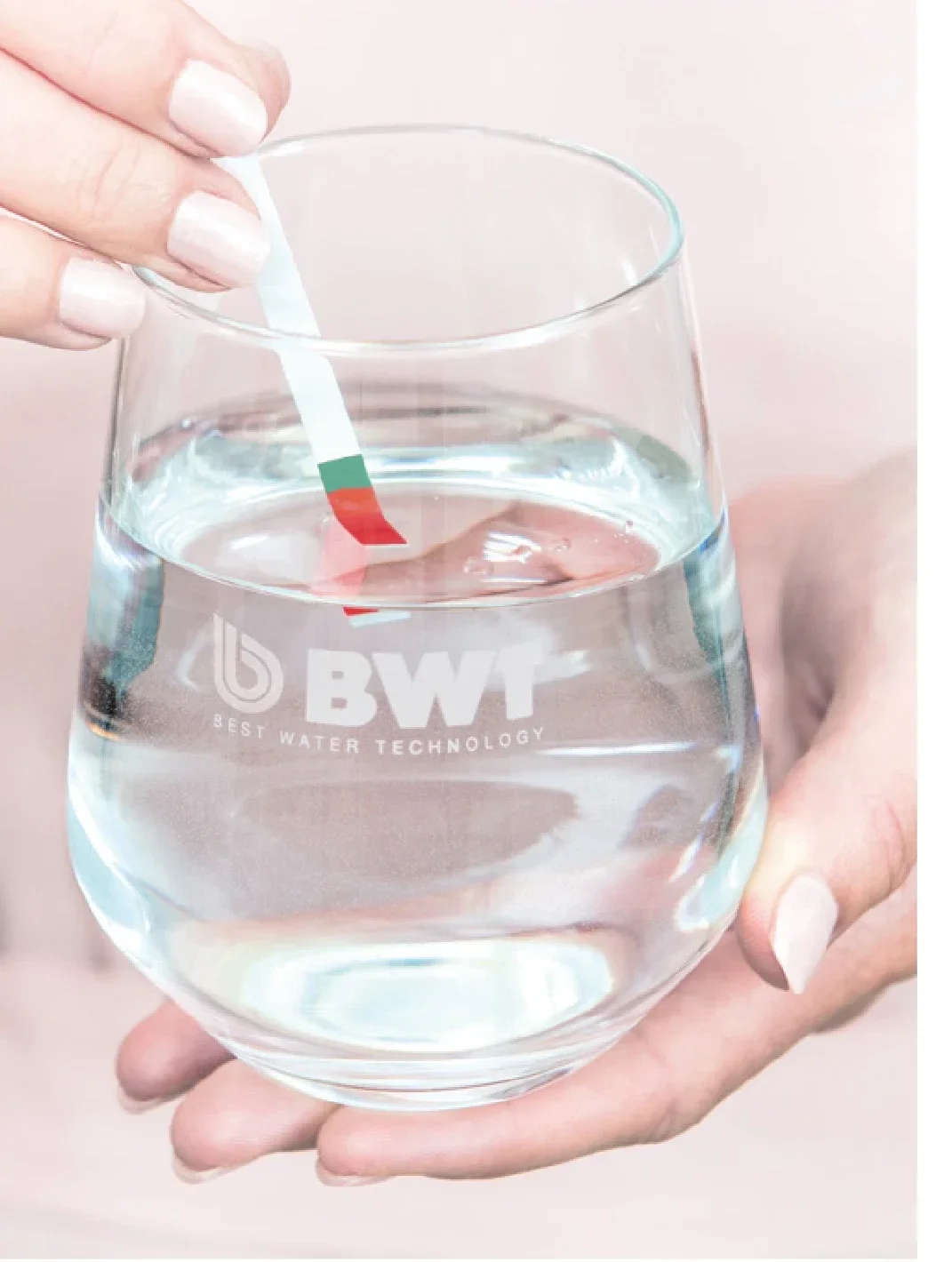 Wasserhärte-Teststreifen wird in ein Glas Wasser gehalten