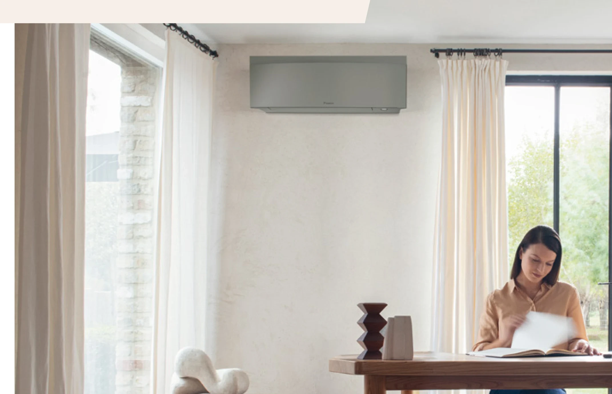 Daikin Emura in Silber in einem hellen Wohnraum mit Vorhang und Holzfußboden