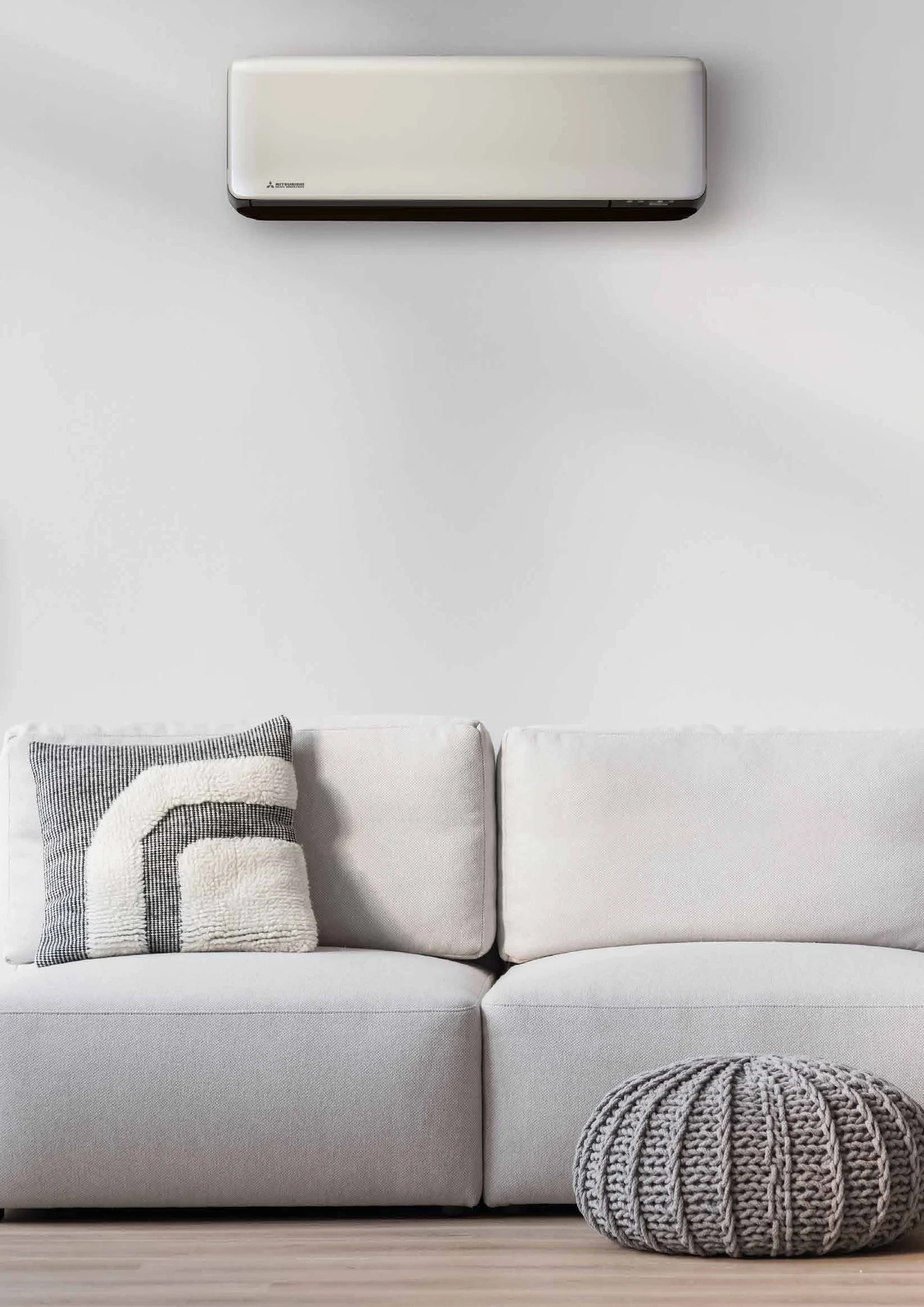 Helles Wohnzimmer mit hellem Sofa und einem schlanken SRK ZT-Wandgerät von Mitsubishi Heavy Industries